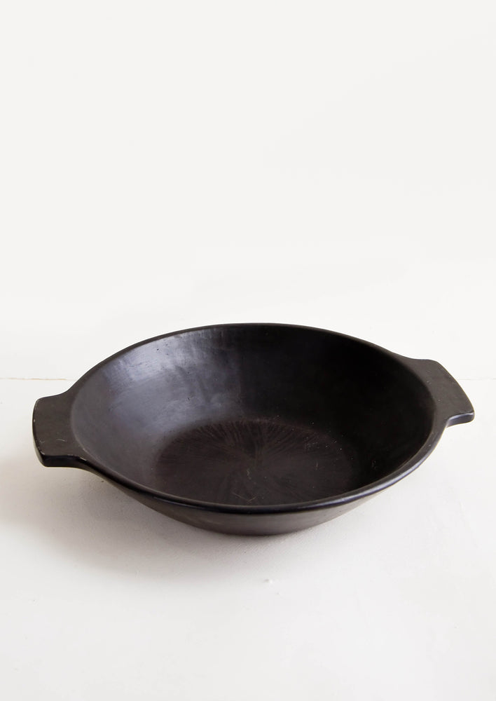 Shallow serving bowl in black with solid rectangular handles at sides