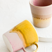 3: Ceramic coffee mugs in pink, yellow and brown tones.