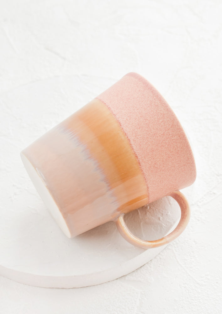 Pink / Beige: A coffee mug with a handle in pink, yellow and brown.
