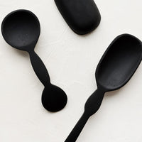 1: An assortment of carved black wooden spoons in a mix of shapes and sizes.