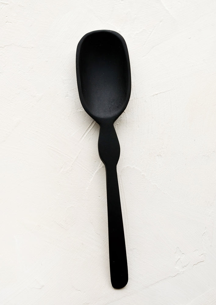 A carved black wooden spoon with decoratively curved handle.