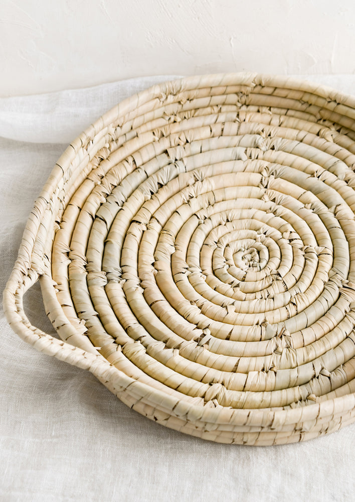 A round and shallow woven palm leaf tray.