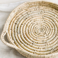 1: A round and shallow woven palm leaf tray.