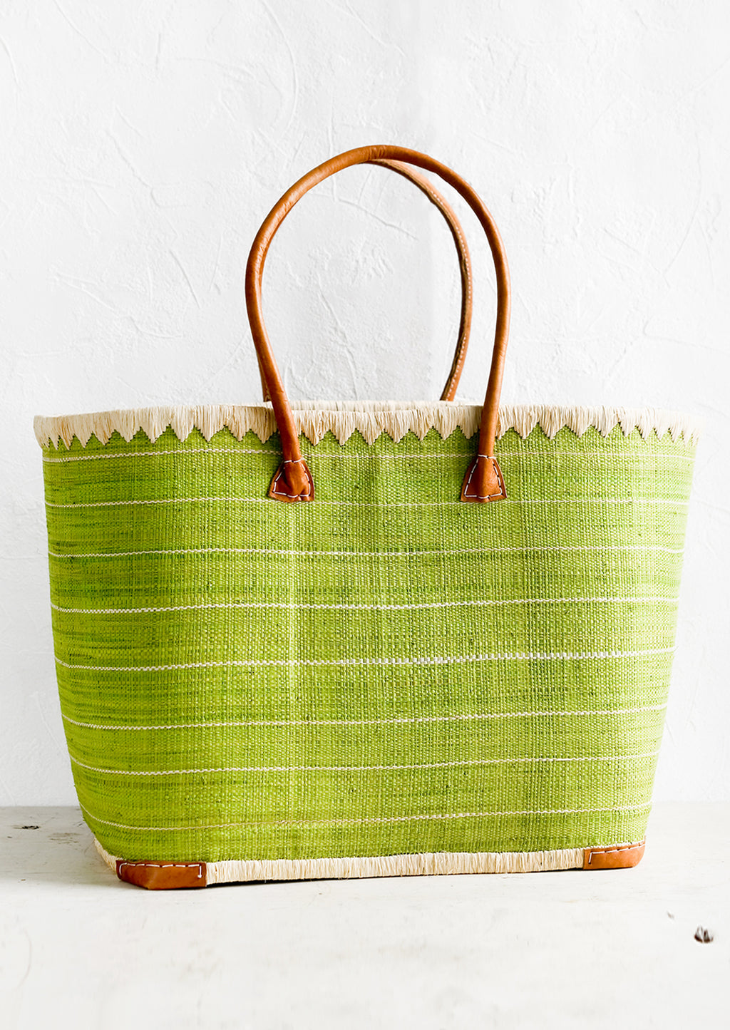 1: A raffia tote bag in green stripes with leather handles.