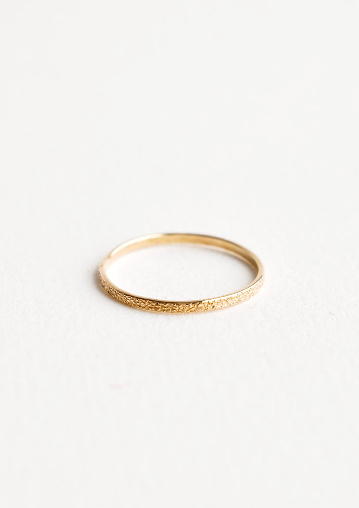 Slim yellow gold ring with textured surface.
