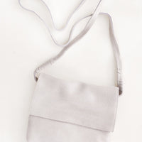 Putty: Pale gray soft leather bag with cross body strap and metallic sheen.