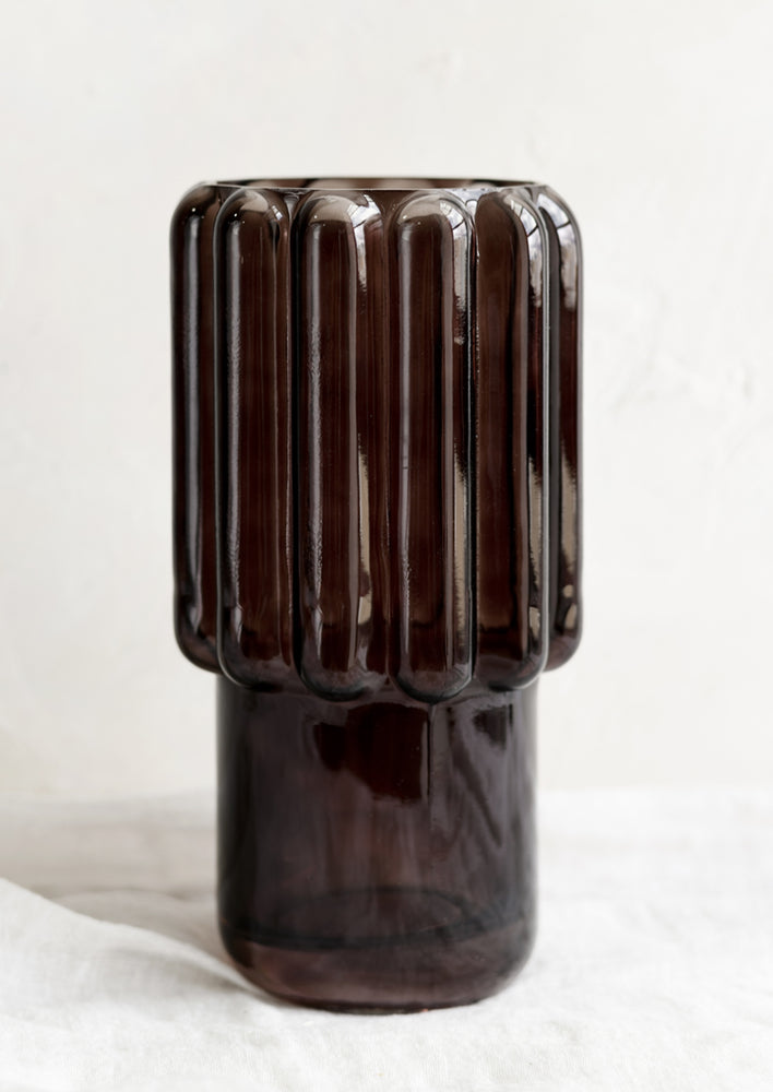 A large glass vase in dark brown with fluted texture.