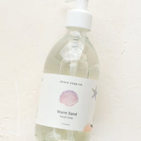 Warm Sand: A glass pump bottle containing liquid soap in "Warm sand" scent.