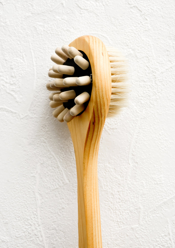 A two-sided wooden shower brush with wooden massager pegs on one side and boar bristle on the other.