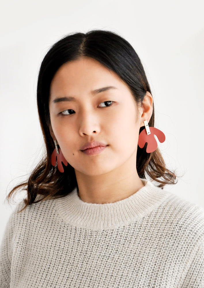 Model shot wearing earrings and a white sweater.