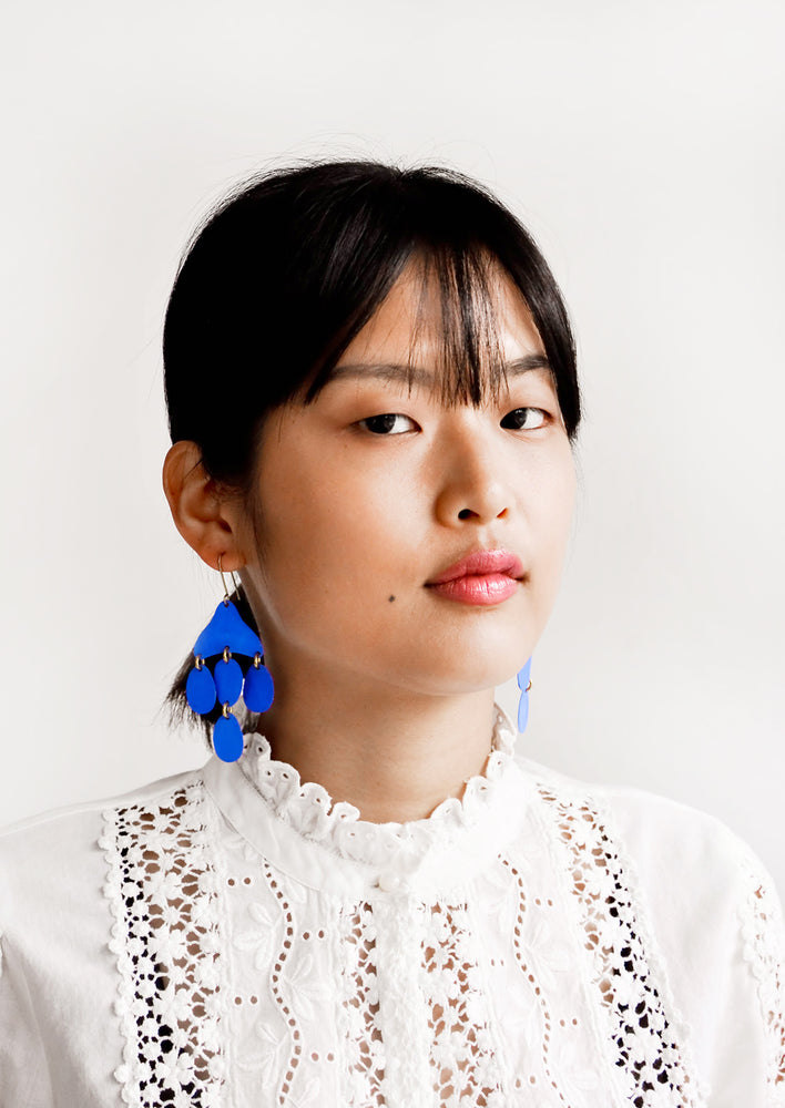 3: Model shot showing woman wearing earrings and a white top.