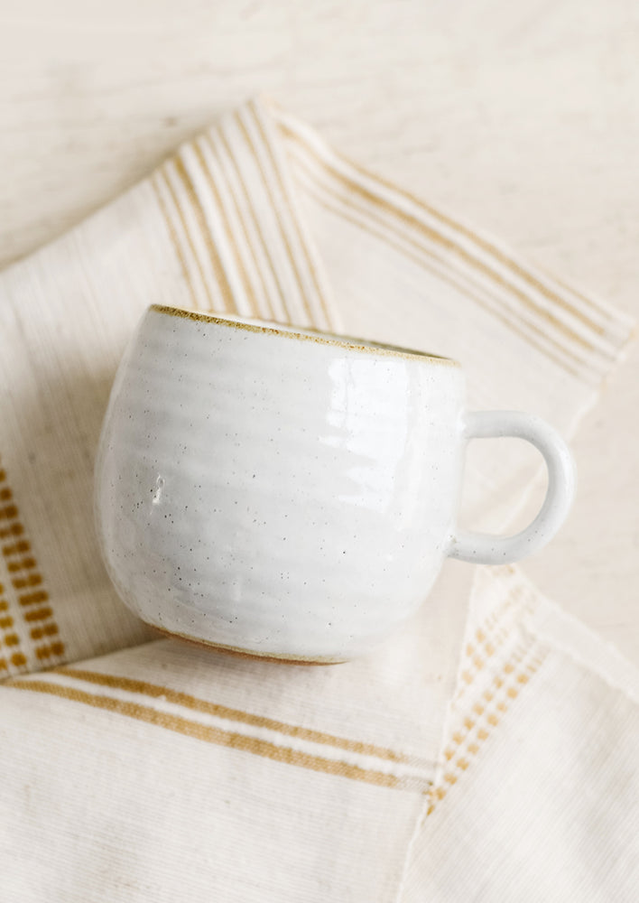 A round coffee mug in softly speckled glossy white glaze.