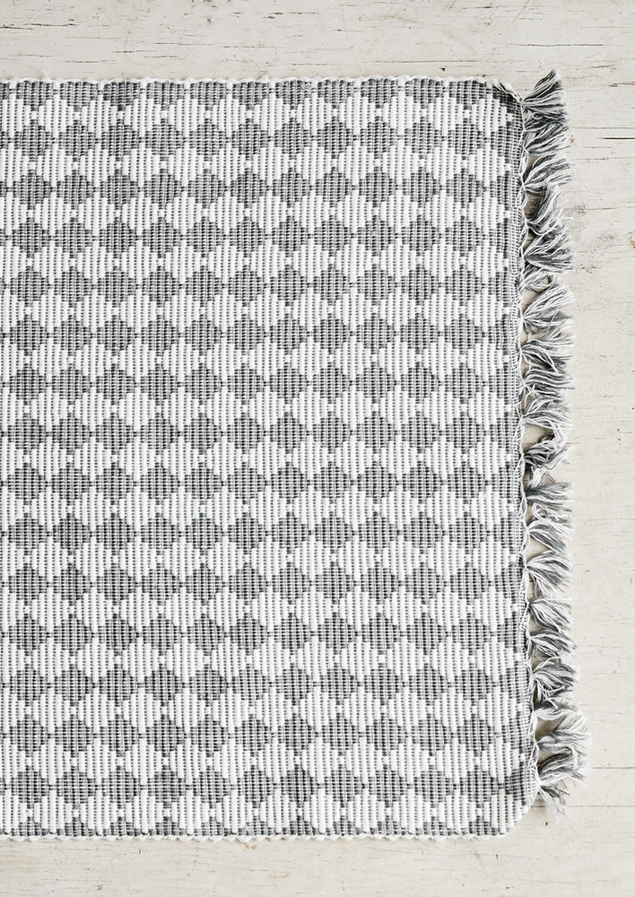 A grey and white placemat with triangular checkered pattern.