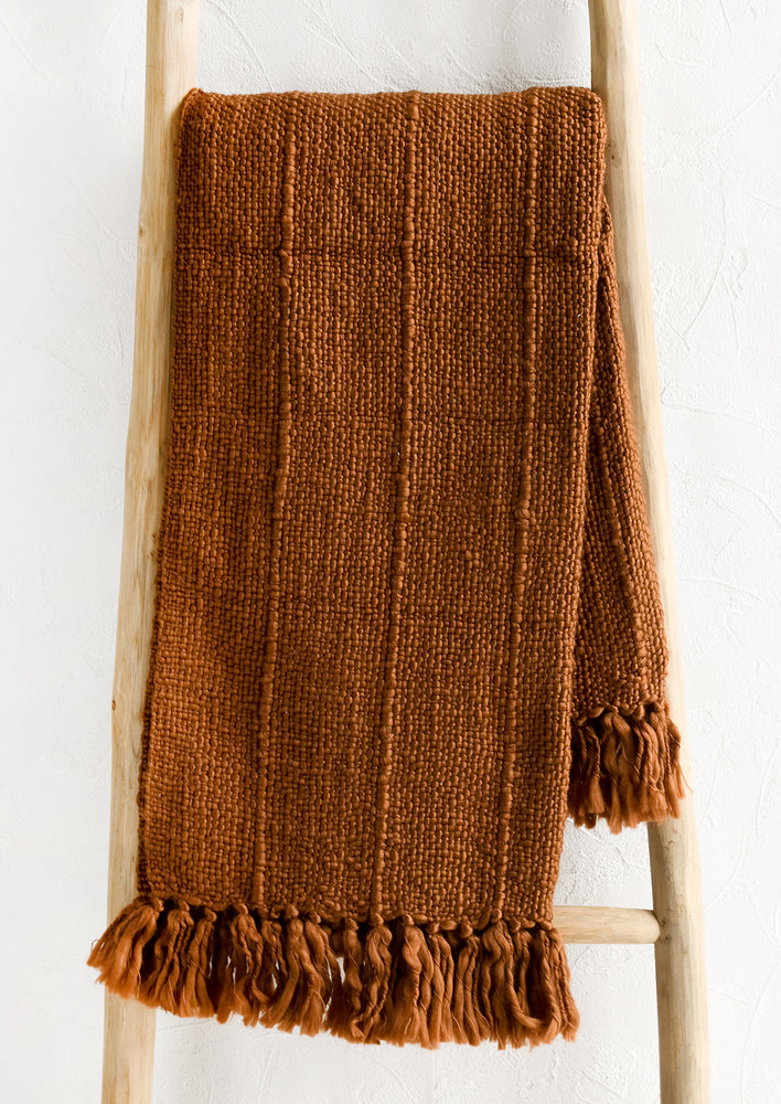 1: A rust colored cotton throw with boucle weave.