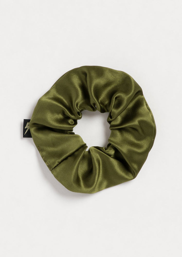 A silk scrunchie in army green with lightning bolt logo tag.