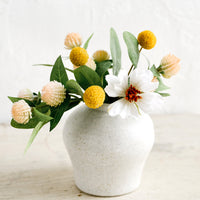2: A small white ceramic vase in curvy shape with colorful flowers.