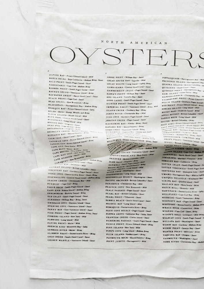 1: A white linen tea towel with black text listing out oyster types and their origins.