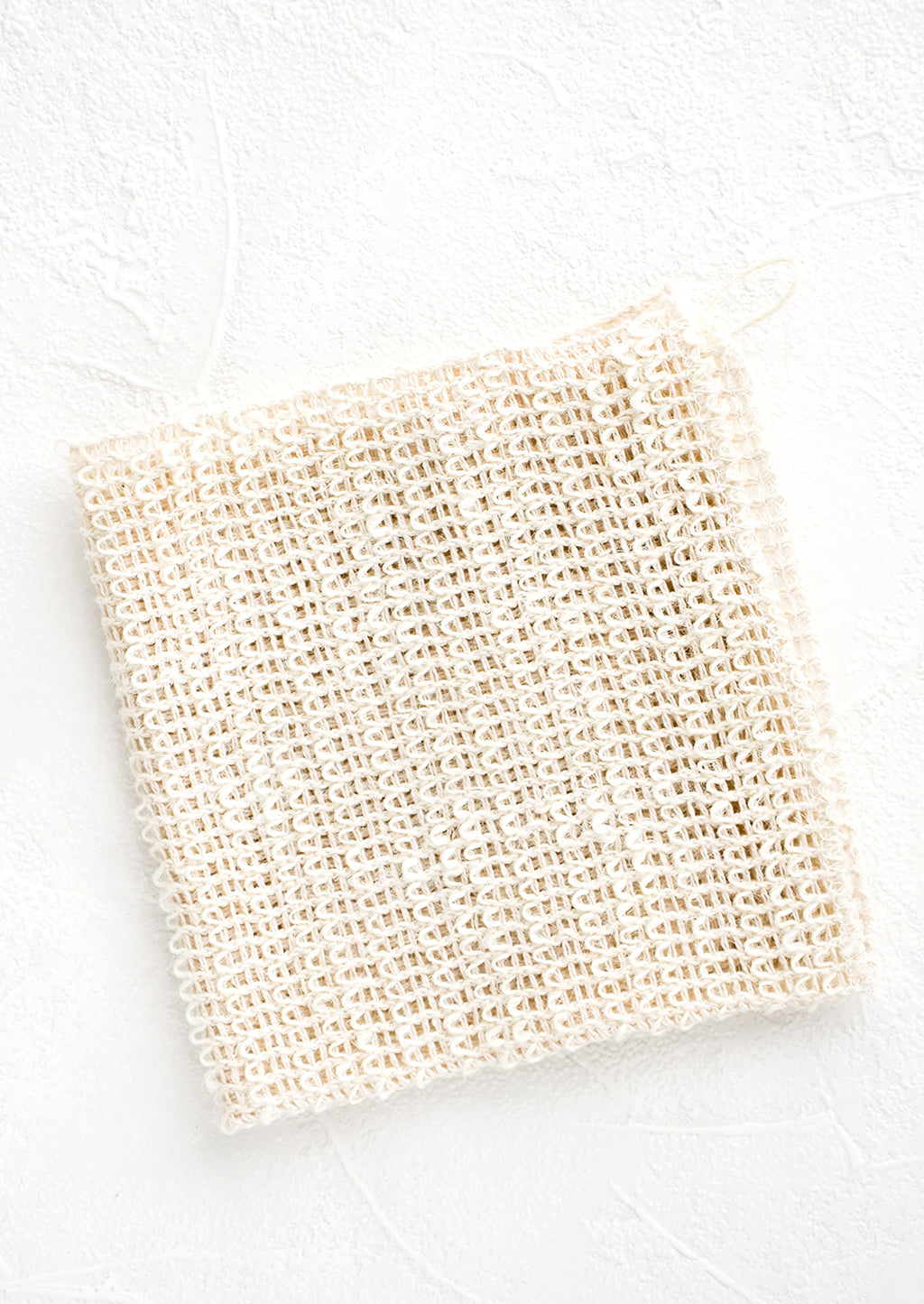 2: A folded washcloth made from natural sisal with a hanging loop at one corner.