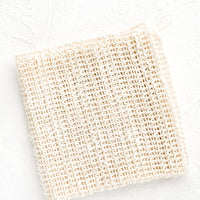 2: A folded washcloth made from natural sisal with a hanging loop at one corner.