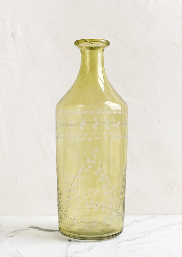 A green bottle shaped glass vase with leaf etching.