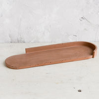 3: An elongated oval shaped platter made from rust colored concrete.