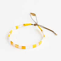 Yellow: Bracelet featuring flat yellow and white glass beads interspersed with flat gold bead on an adjustable cord.