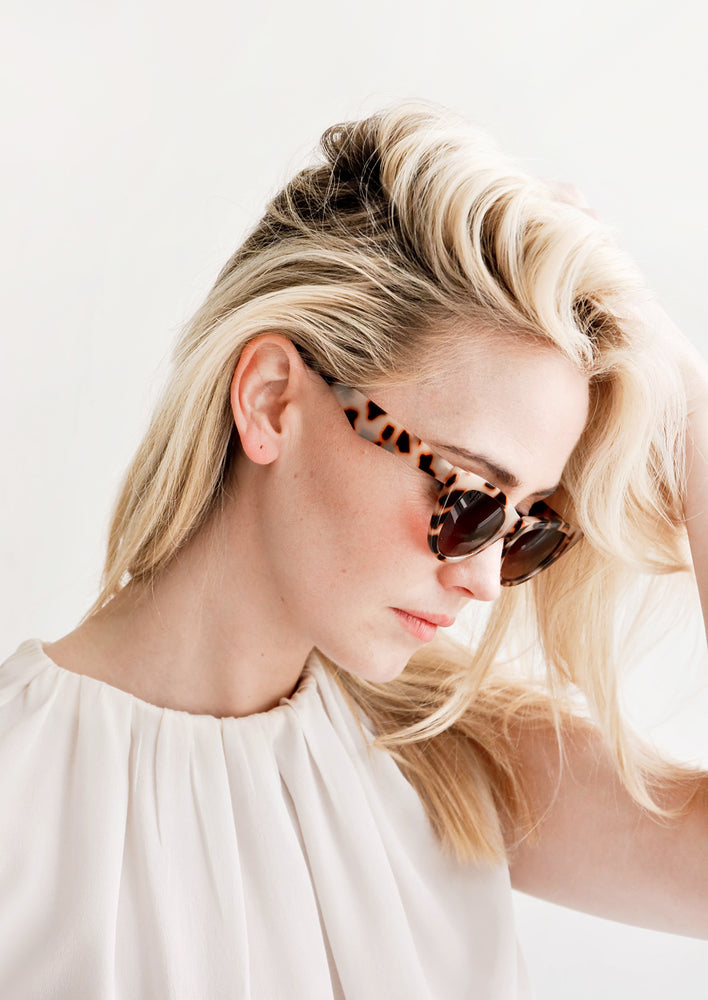 2: Model shot showing woman wearing sunglasses and white top.