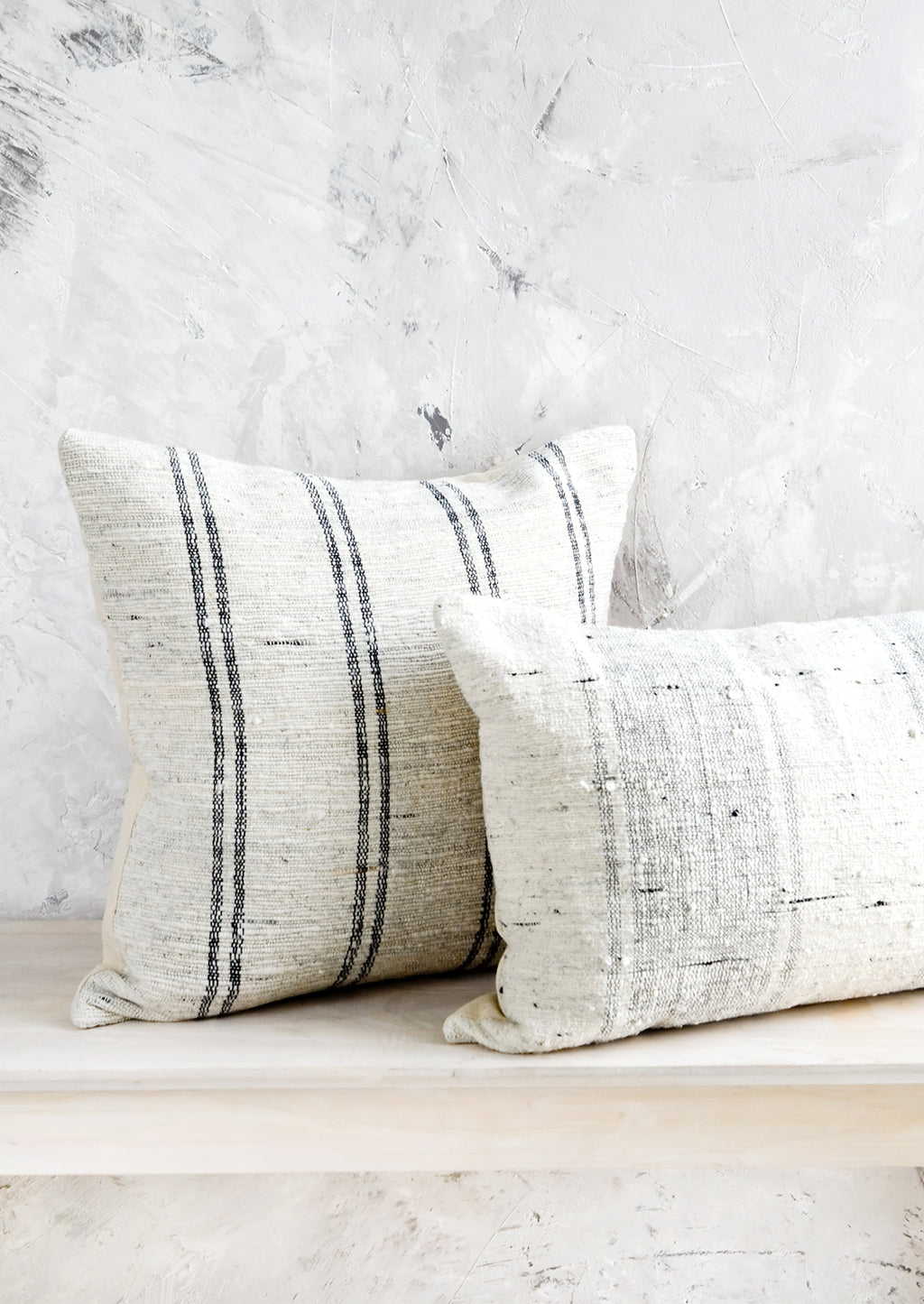 2: Square and lumbar throw pillows in white slub fabric with grey or black stripes.