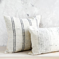 2: Square and lumbar throw pillows in white slub fabric with grey or black stripes.