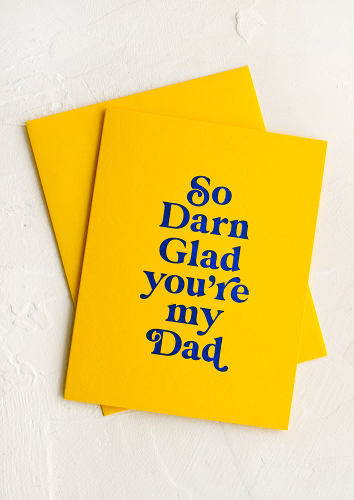 1: A yellow greeting card and yellow envelope, card reads "So darn glad you're my dad" on front.