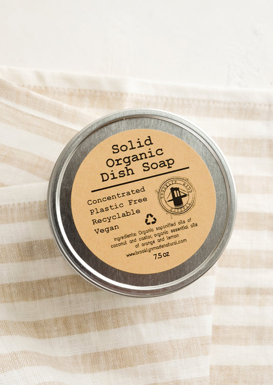 A metal tin containing solid dish soap.