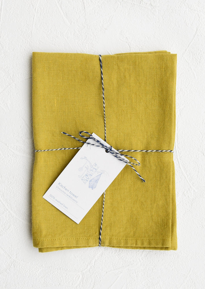 Chartreuse: A folded chartreuse linen tea towel tied in baker's twine with a decorative hangtag