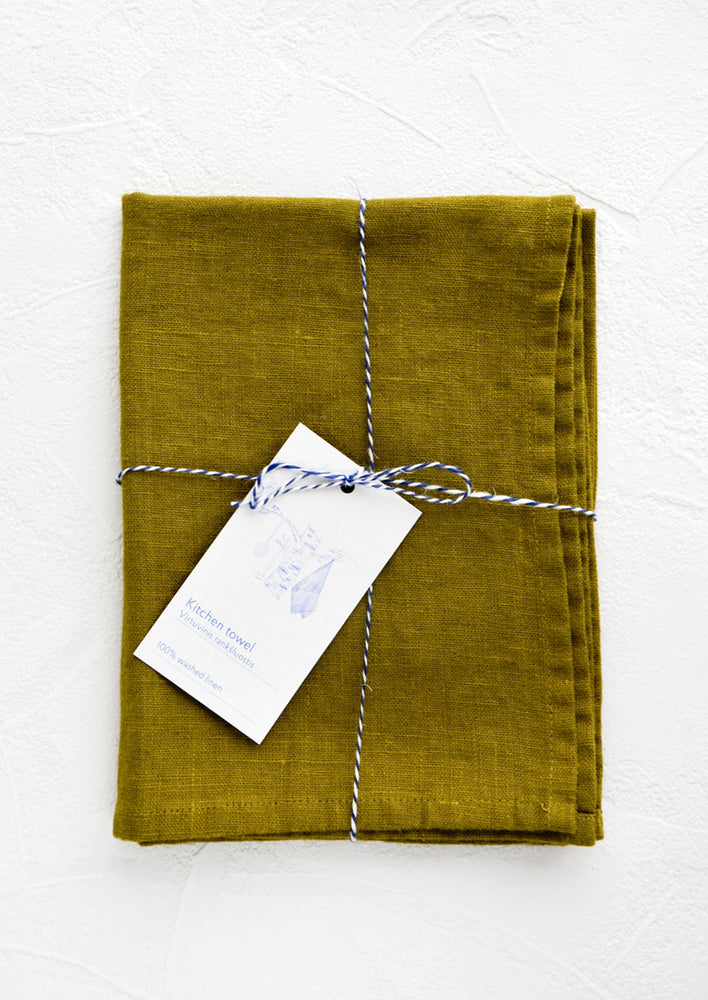 A folded green linen tea towel tied in baker's twine with a decorative hangtag.