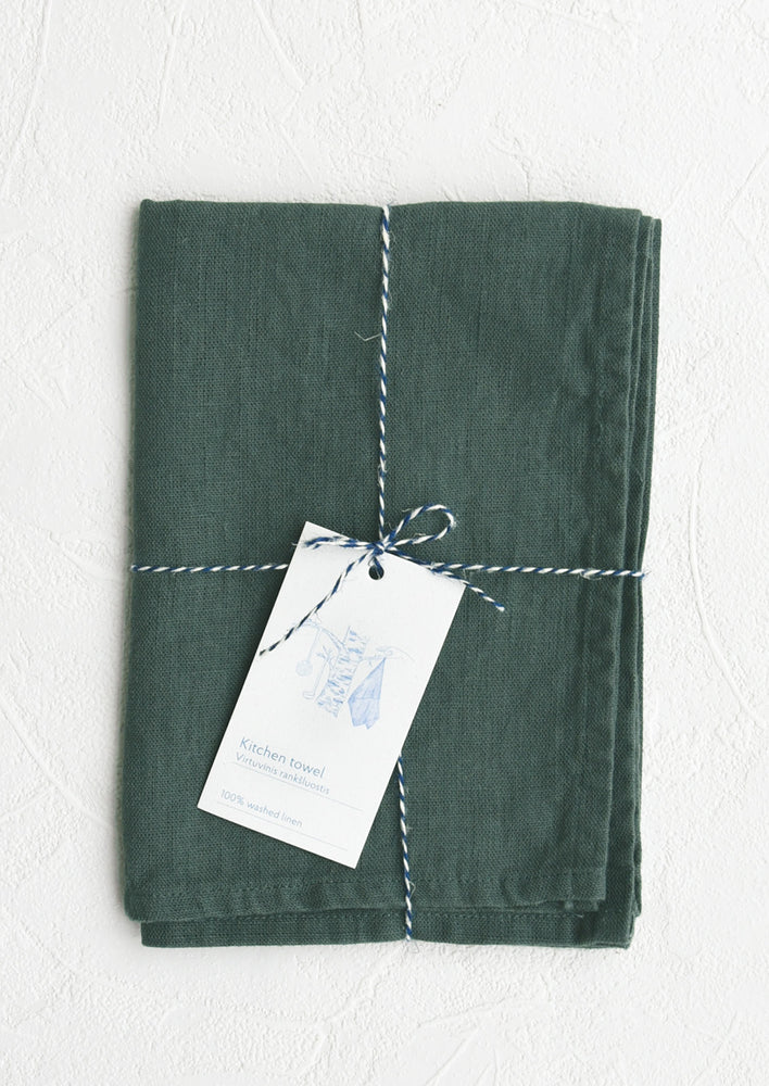 Juniper: A folded dark teal linen tea towel tied in baker's twine with a decorative hangtag