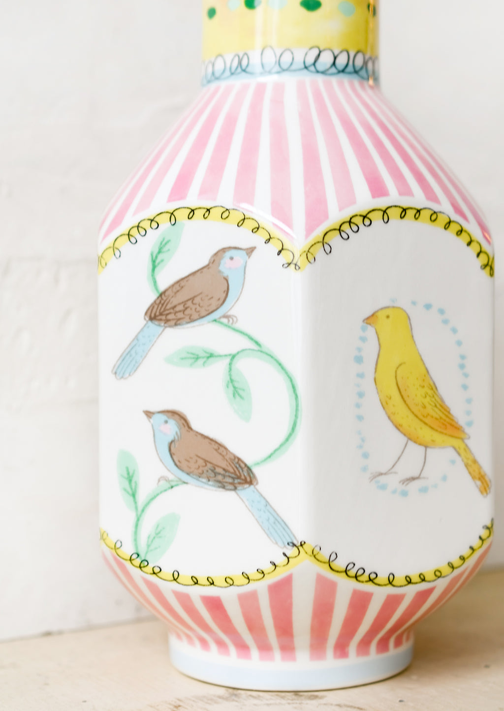 3: A graphic print vase with pink stripes and three-dimensional shape with bird motif.
