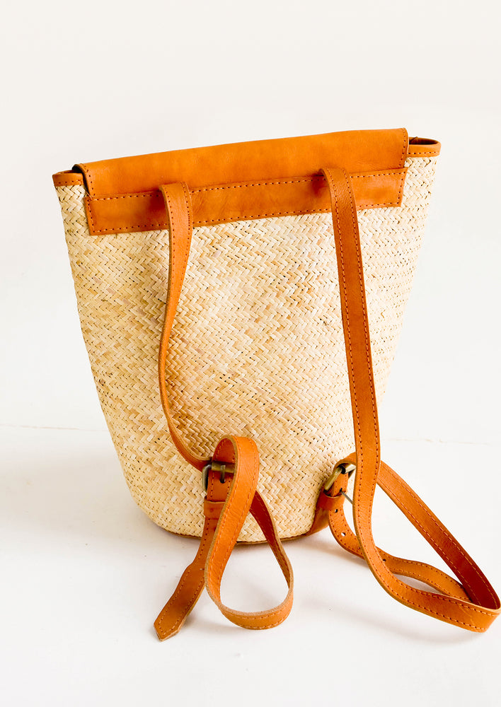 Woven straw backpack with tanned leather details and straps