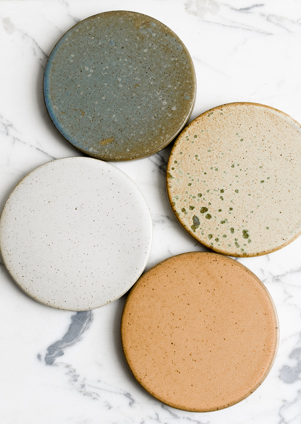 1: A set of four round ceramic coasters in earthy color mix.