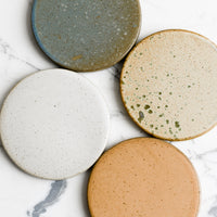 1: A set of four round ceramic coasters in earthy color mix.