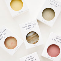 1: Six bar soaps laid out in white packaging with circular cutouts to show their various colors and textures.