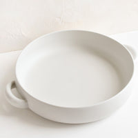 1: A round, shallow extra large serving bowl in white ceramic with curved handles at sides.
