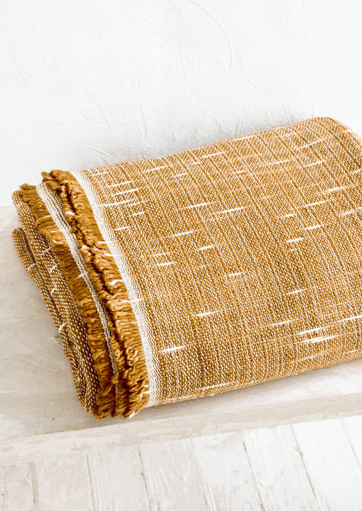 Woven blanket with fringed edge and space-dye weave pattern.