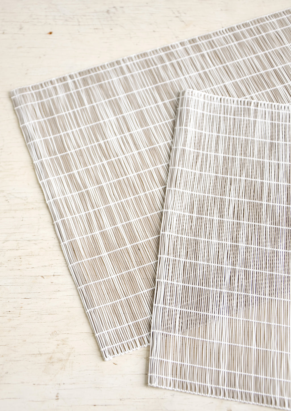 Taupe: A pair of placemats made from intertwined, vertically woven vinyl in taupe and white.