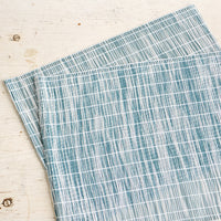 Teal: A pair of placemats made from intertwined, vertically woven vinyl in teal and white.