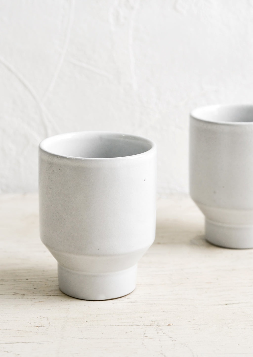 1: Glossy white ceramic cups with geo tapered bottom.