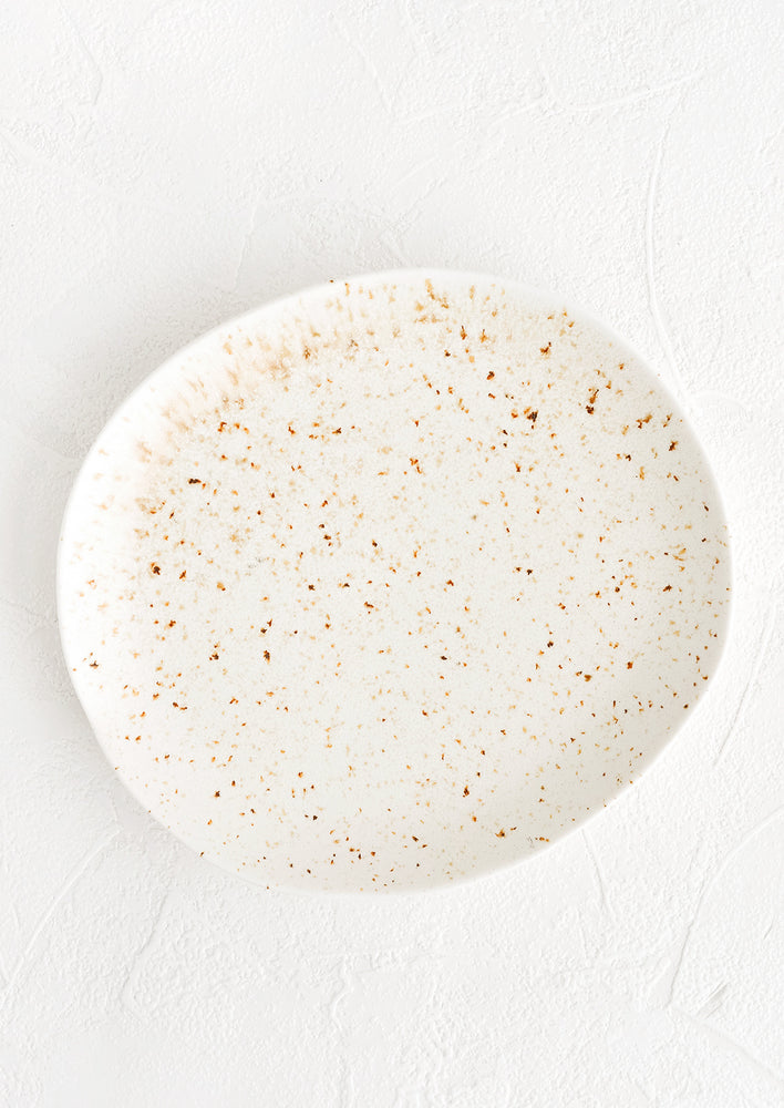 1: A ceramic plate in white with brown flecks in an organic, subtly asymmetrical round shape.