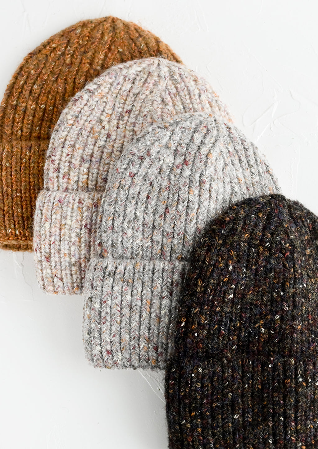 2: Four speckled yarn beanies in assorted colors.