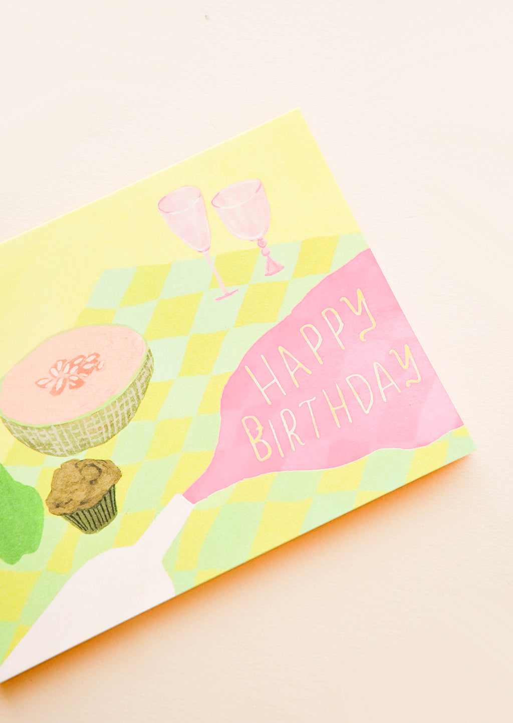 2: Greeting card with picnic setting, neon pink spilled wine puddle has letters reading "Happy Birthday"