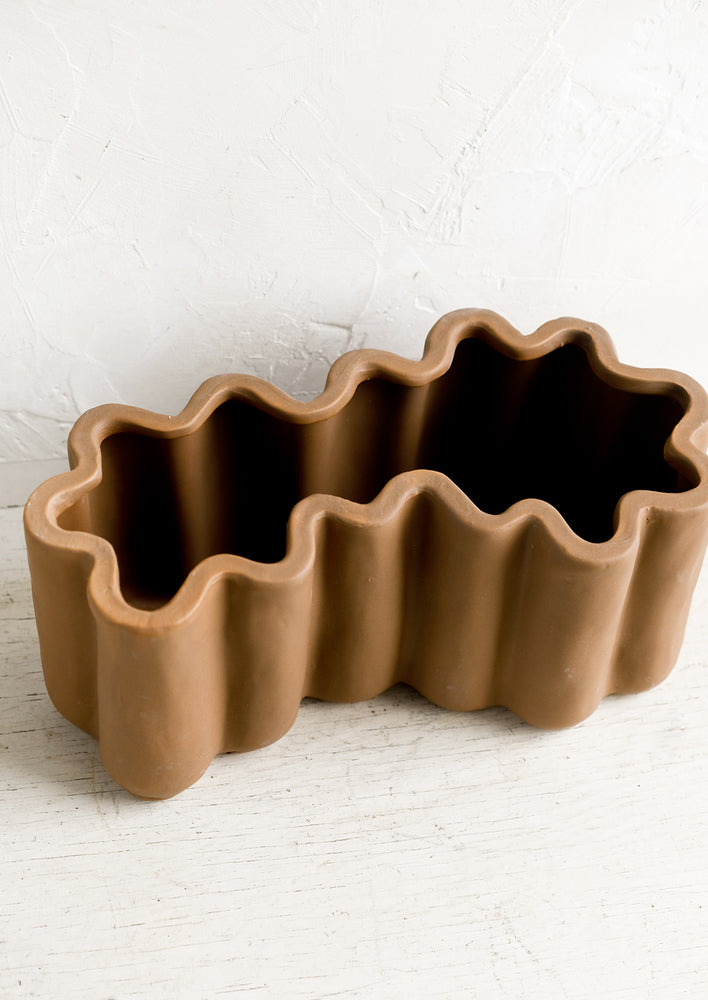A brown ceramic planter in squiggle shape.