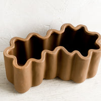 3: A brown ceramic planter in squiggle shape.