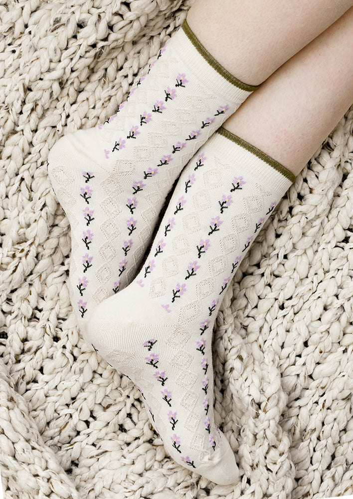 A pair of cream socks with purple flower vertical lines.